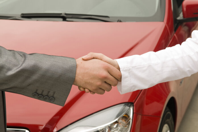 Acheter une voiture d'occasion poignée de main devant la voiture