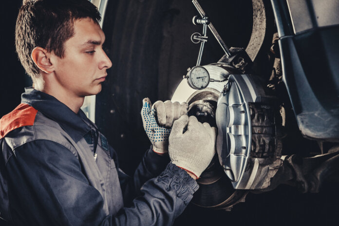 Mécanicien automobile professionnel réparant des freins dans un atelier de réparation automobile.