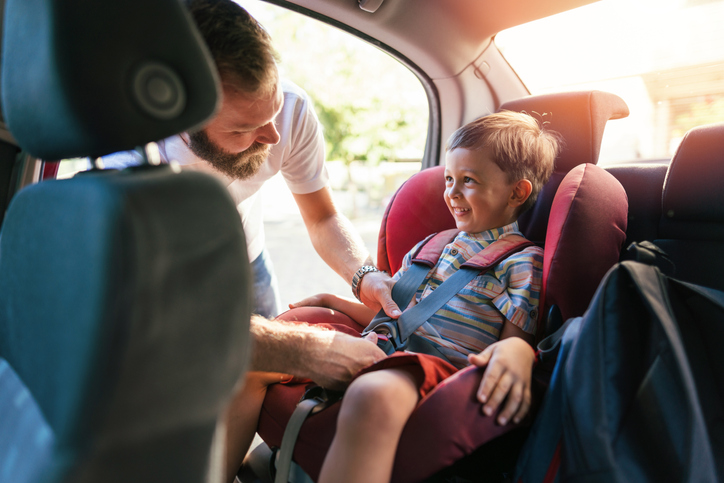 Un père en voyage avec son fils sur un siège auto.